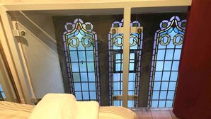 A bedroom with a bed, a window with stained glass, and a door. - Church Conversion 3-bed House in Centre of Kendal (Kendal)
