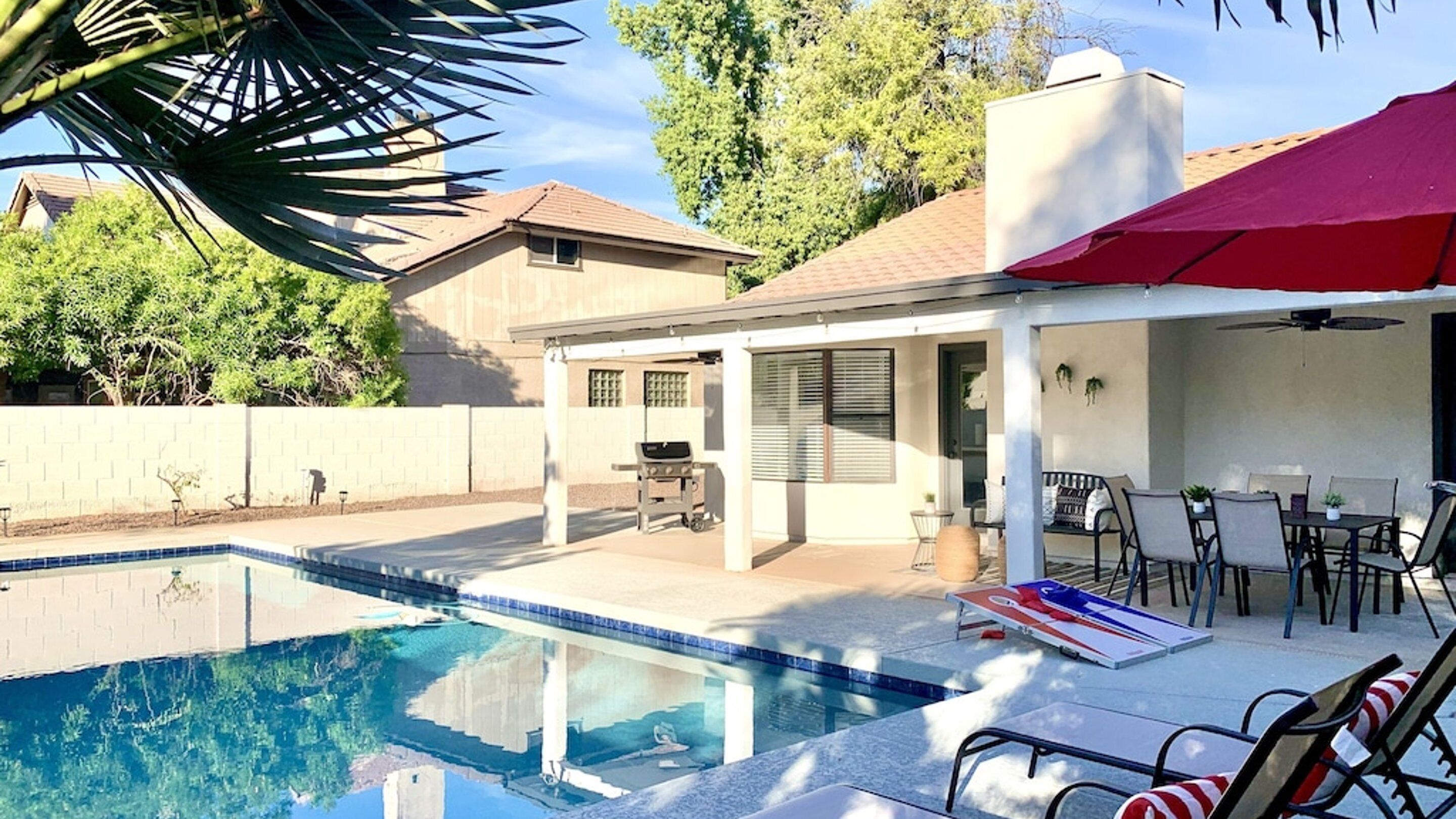 A backyard with a swimming pool, patio furniture, and a covered seating area.
