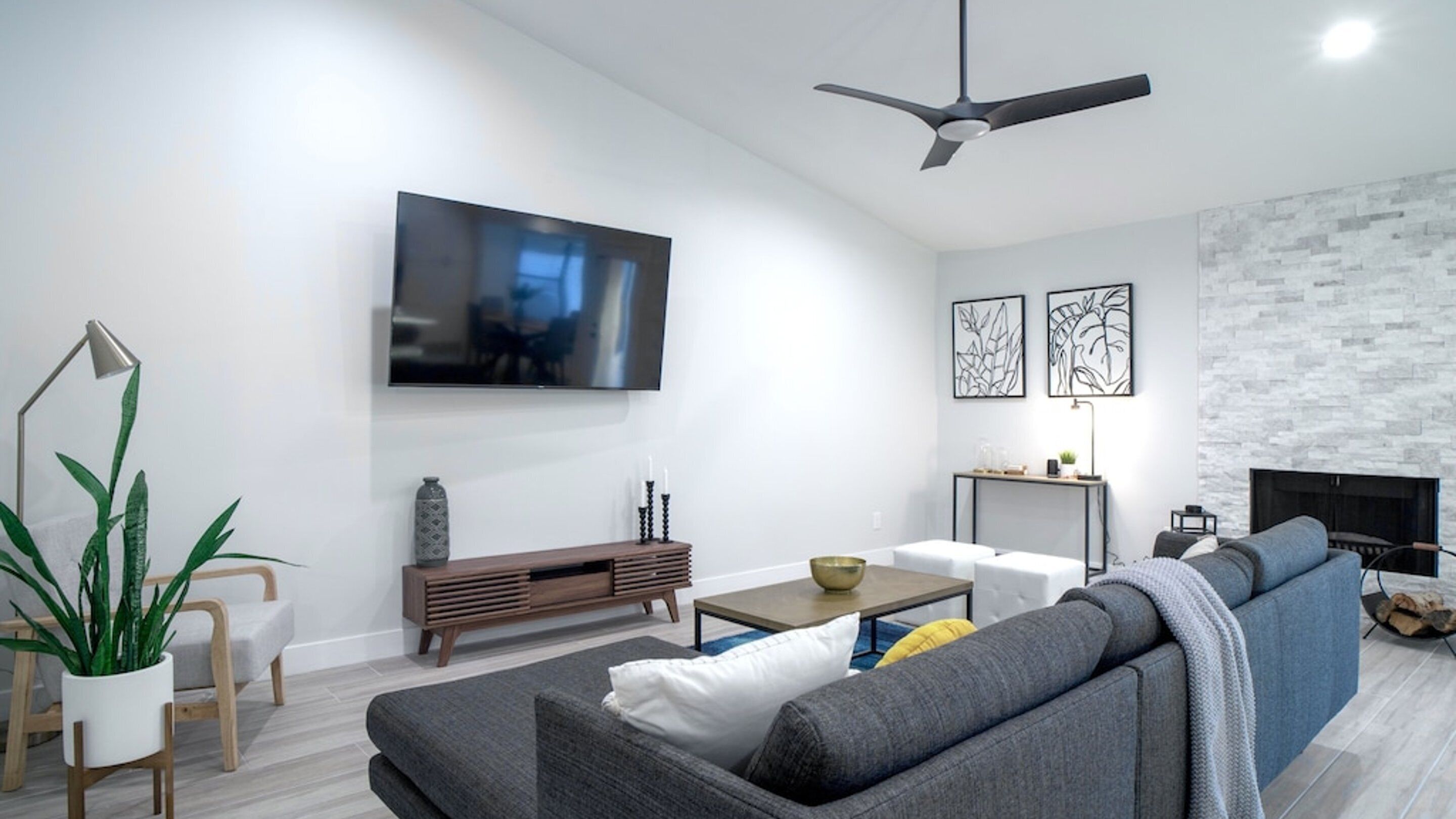 A modern living room with a flat-screen TV, a sofa, a coffee table, and a fireplace.