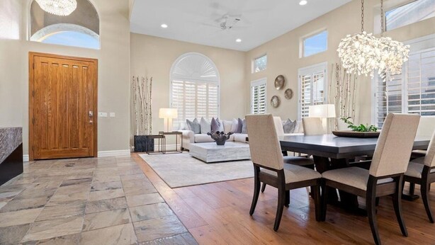 A spacious dining area with a wooden table and chairs, a chandelier, and a view of the living room. - Massive North Scottsdale 6 Bdrm w/ Oasis Backyard! (Scottsdale)