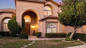 A two-story house with a central entrance, arched windows, and a well-maintained lawn. - Massive North Scottsdale 6 Bdrm w/ Oasis Backyard! (Scottsdale)