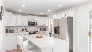 A modern kitchen with white cabinetry, a stainless steel refrigerator, a microwave, and a gas stove. - NEW 7bdrm-4ba Million+ Estate W/amazing Amenities (Phoenix)
