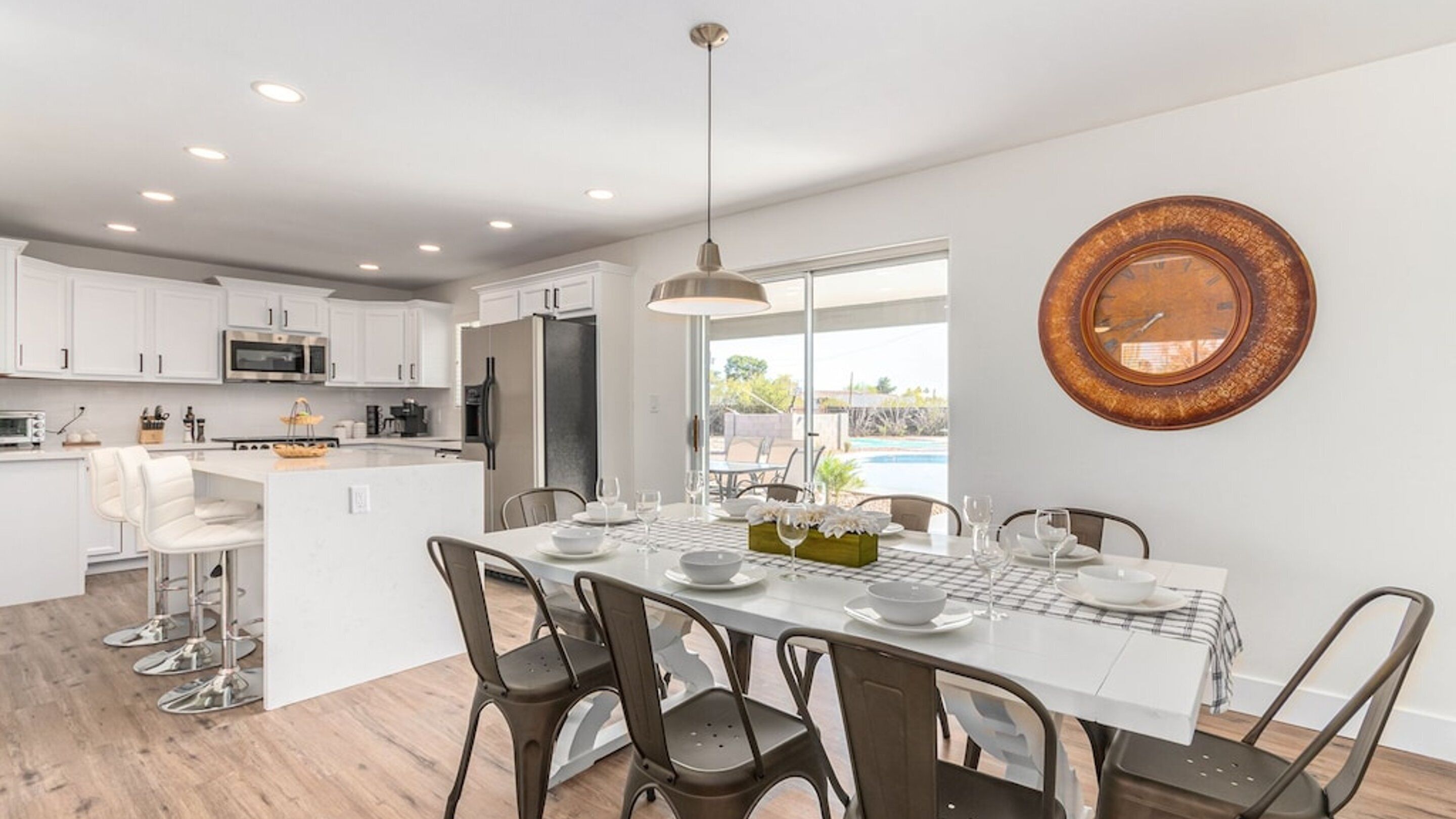 A modern kitchen with white cabinets, stainless steel appliances, and a dining area with a white table set for four.
