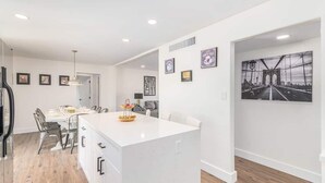 A modern kitchen with a central island, dining area with chairs, and a large black and white artwork on the wall. - NEW 7bdrm-4ba Million+ Estate W/amazing Amenities (Phoenix)