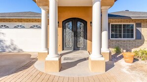A house with a covered entrance, a brick facade, and a black door with decorative glass panels. - NEW 7bdrm-4ba Million+ Estate W/amazing Amenities (Phoenix)