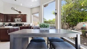 A modern kitchen with dark wood cabinets, stainless steel appliances, and a large window overlooking a garden. - Amazing Home in Great Location W/backyard Oasis! (Scottsdale)