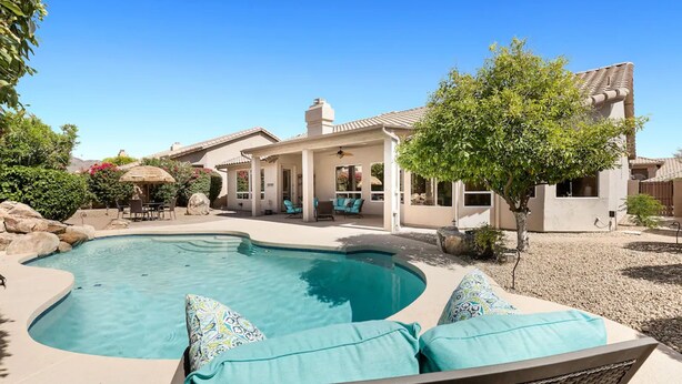 A swimming pool with a curved edge, surrounded by a patio area with outdoor furniture. - Amazing Home in Great Location W/backyard Oasis! (Scottsdale)