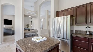 A modern kitchen with granite countertops, stainless steel appliances, and dark wooden cabinets. - Amazing Home in Great Location W/backyard Oasis! (Scottsdale)