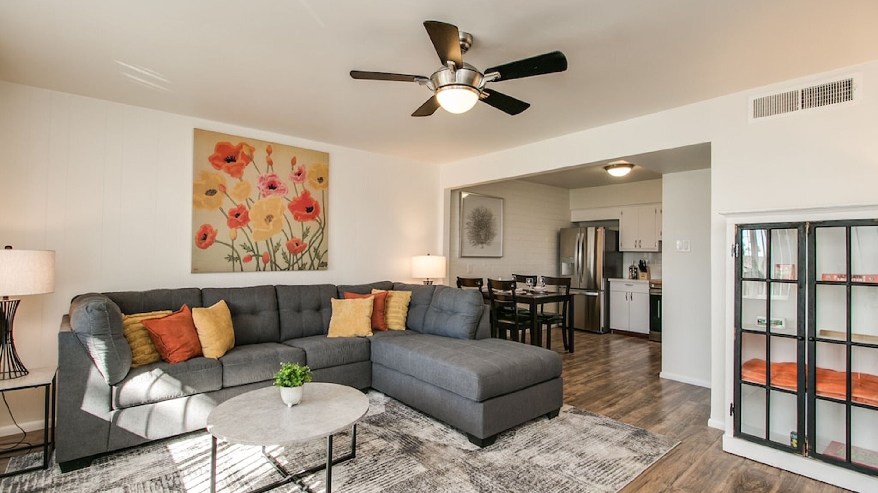 A modern living room with a sectional sofa, a round coffee table, and a ceiling fan.