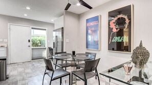 A modern dining area with a glass table and chairs, a refrigerator, and artwork on the walls. - Unbeatable Old Town Location! Modern and Classy! (Scottsdale)