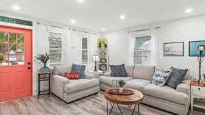 A living room with two sofas, a coffee table, and a red door.