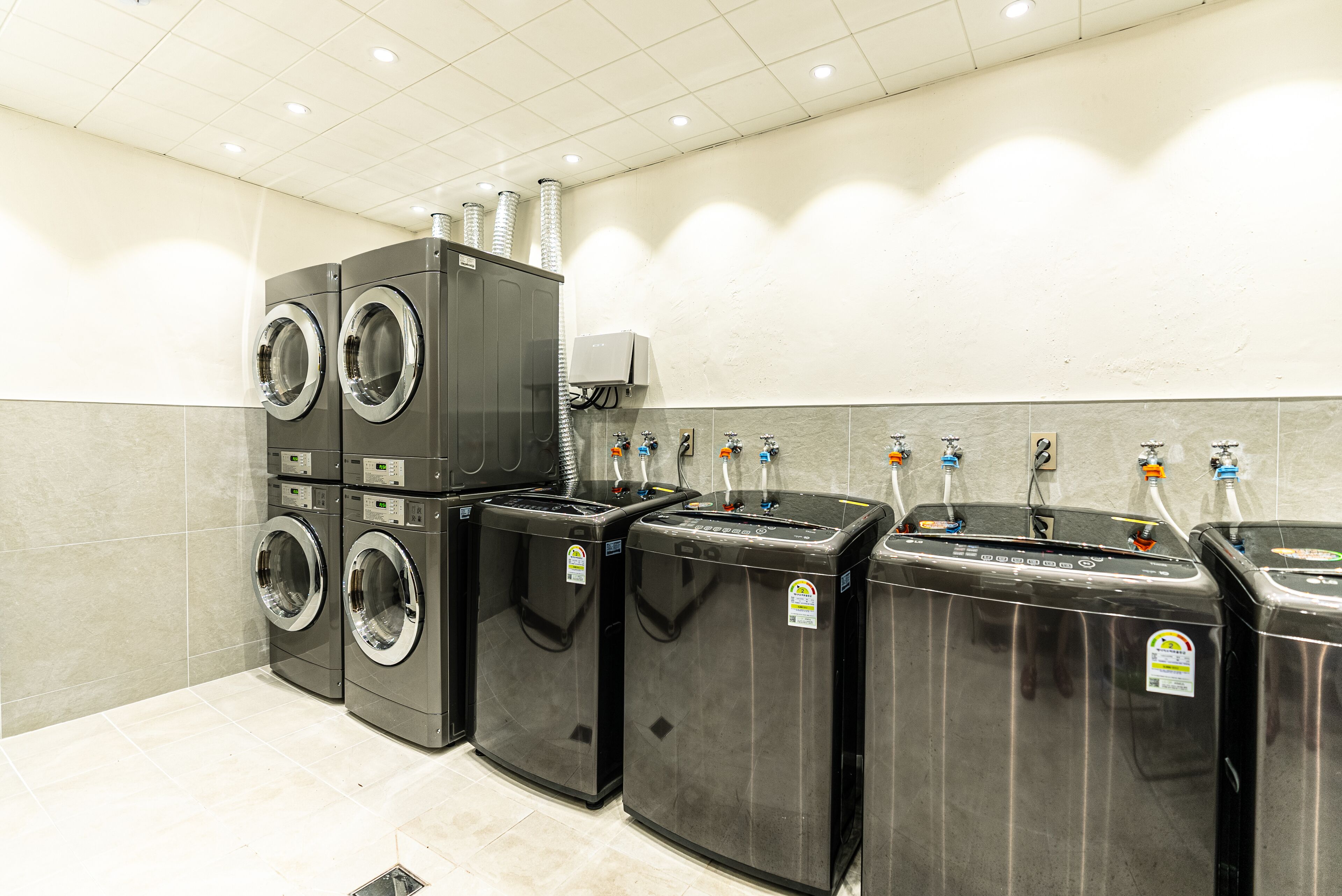 Un cuarto de lavandería con varias lavadoras y secadoras, un sistema de ventilación y una fuente de agua.