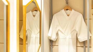 A white robe hanging on a wooden hanger in a room with wooden paneling and a mirror reflecting the robe.