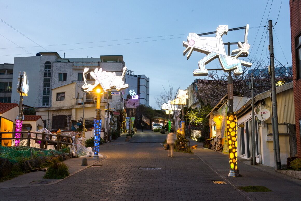 A street with illuminated sculptures and a paved walkway.