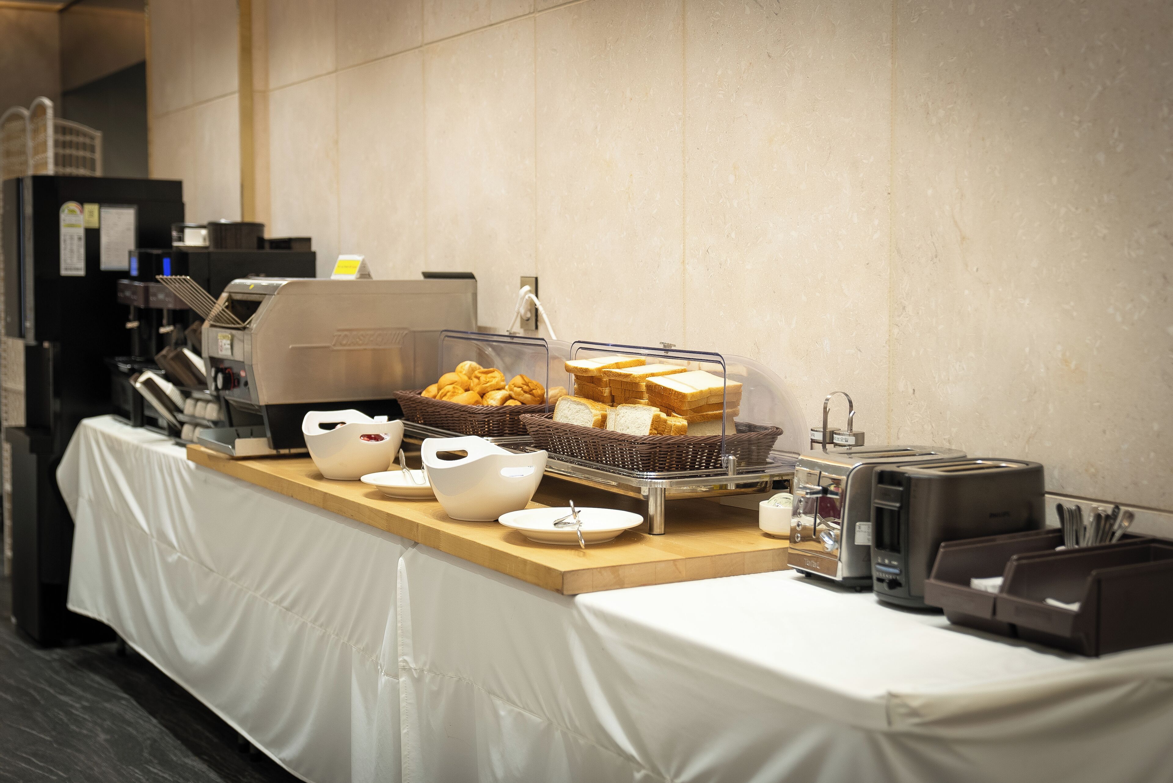 Een buffetopstelling met brood, gebak en een koffieapparaat.