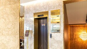 An elevator with a sign listing special floors, a lobby sign, and a chandelier. - Hotel The Grang Seogwipo (Seogwipo)