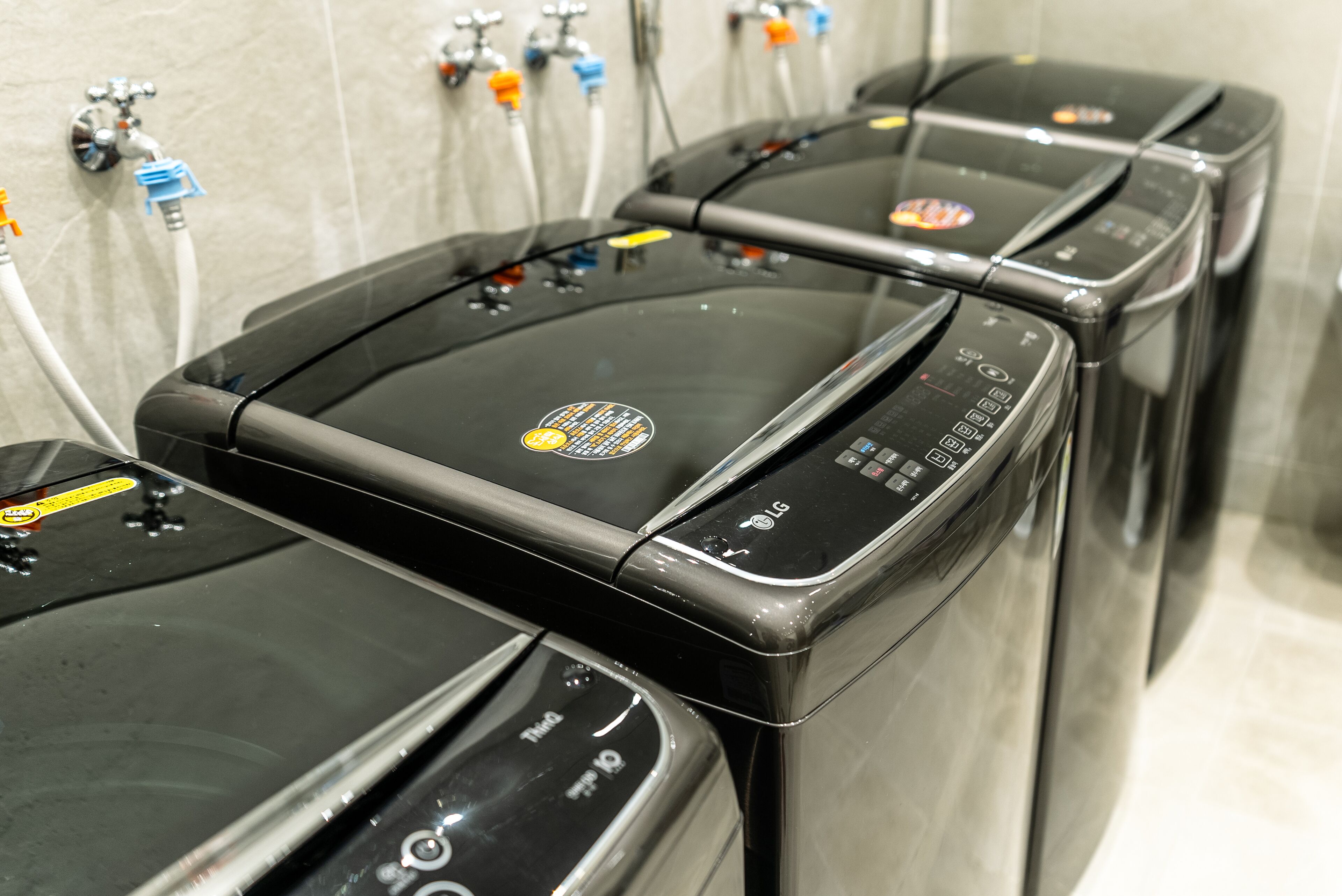 A row of black massage chairs with control panels and water supply connections.