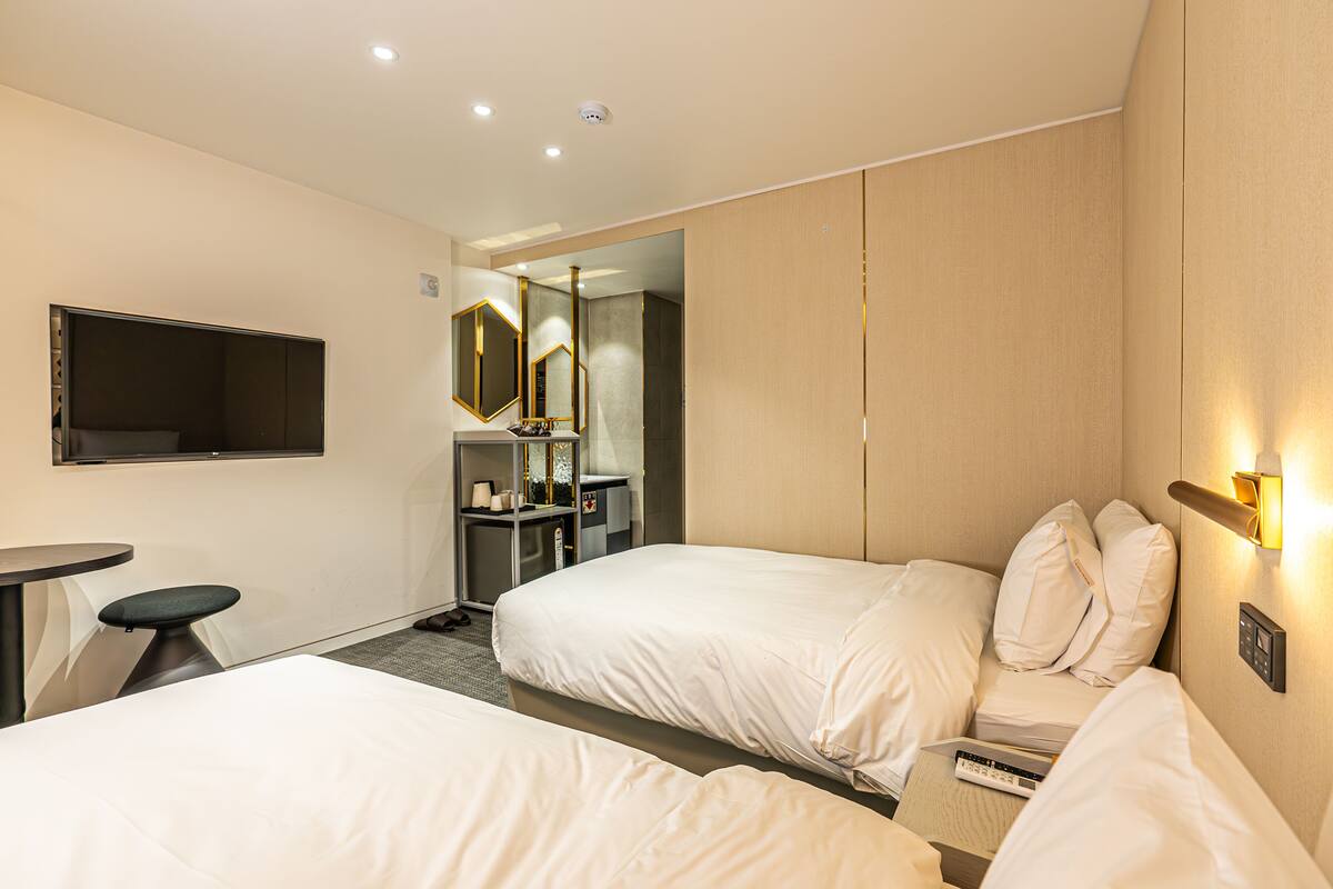 Een hotelkamer met twee bedden, een bureau, een spiegel en een televisie.