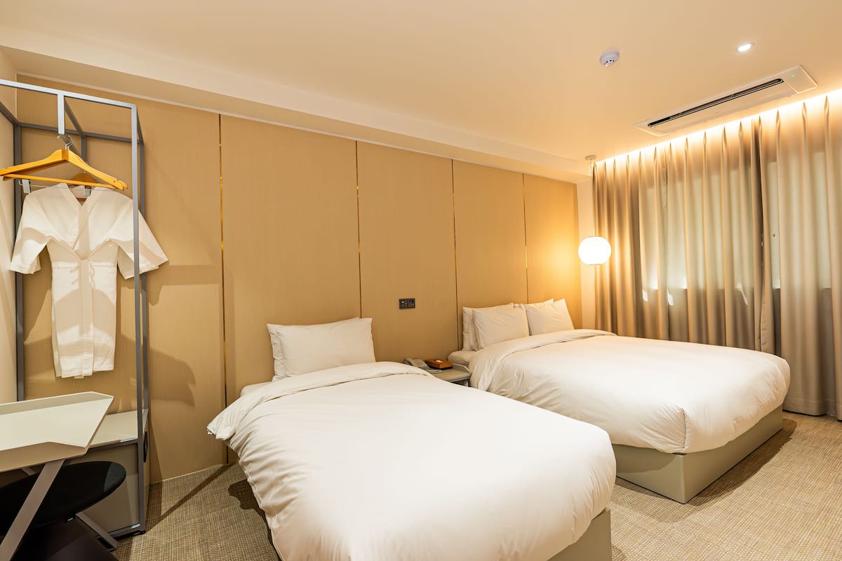 Een hotelkamer met twee bedden, een bureau en een garderobe.