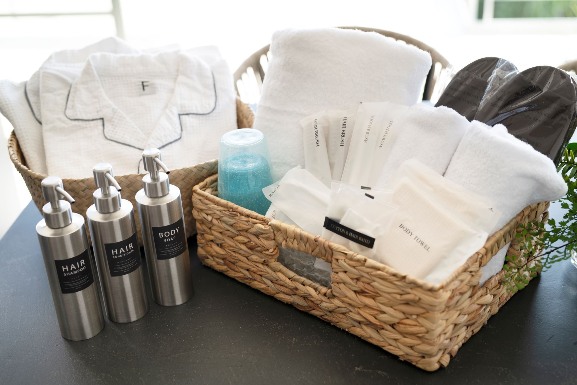 A wicker basket containing hair care products, towels, and a body towel.