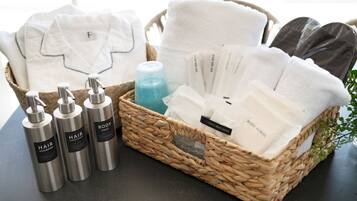 A wicker basket containing hair care products, towels, and a body towel.