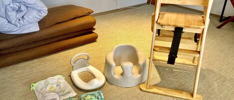 Una habitación con una cama, una silla de madera, un taburete pequeño blanco y un cambiador para bebés.