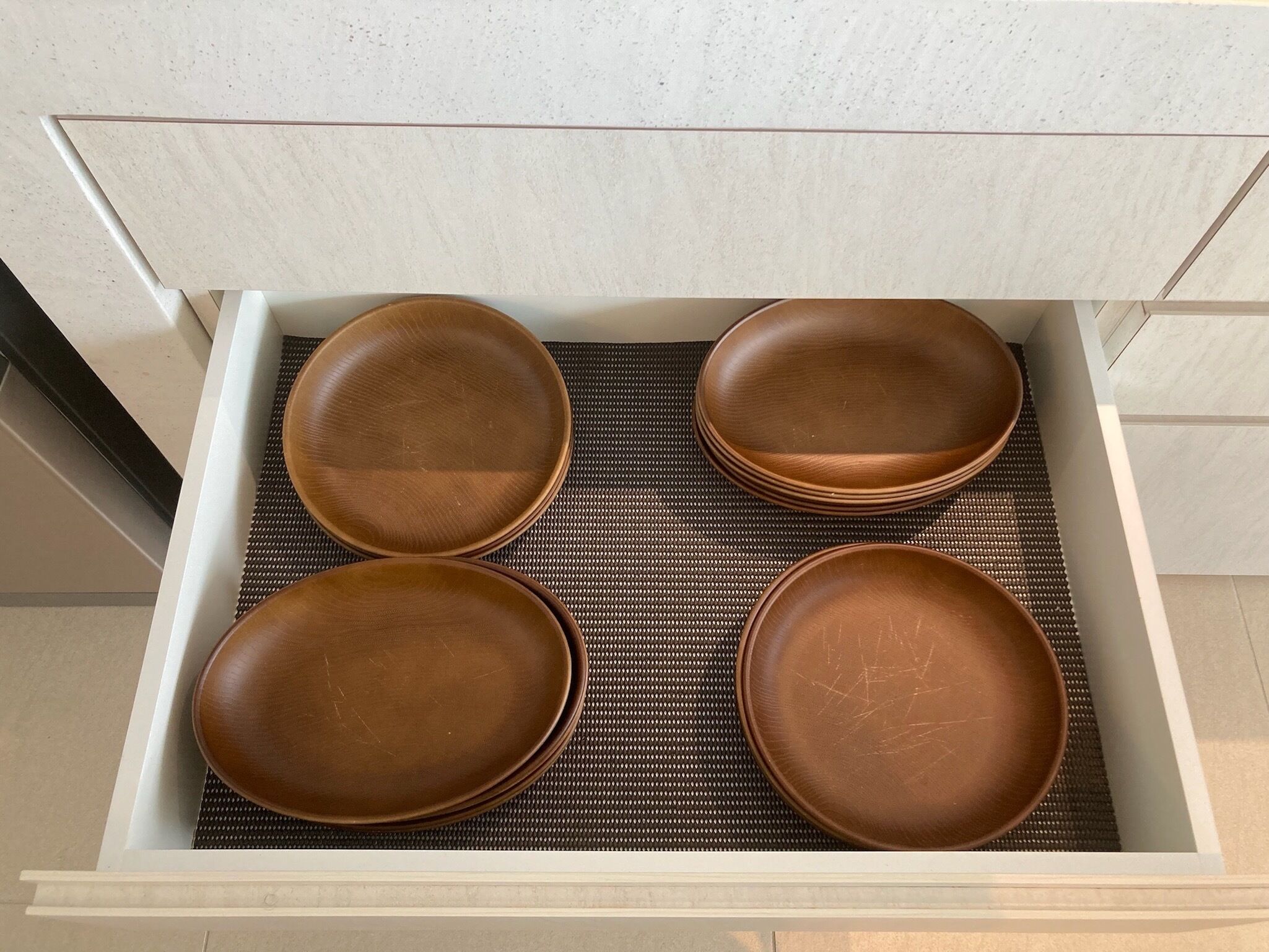 Un tiroir contenant quatre assiettes marron posées sur un tapis tissé.
