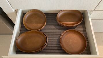 Un tiroir contenant quatre assiettes marron posées sur un tapis tissé.