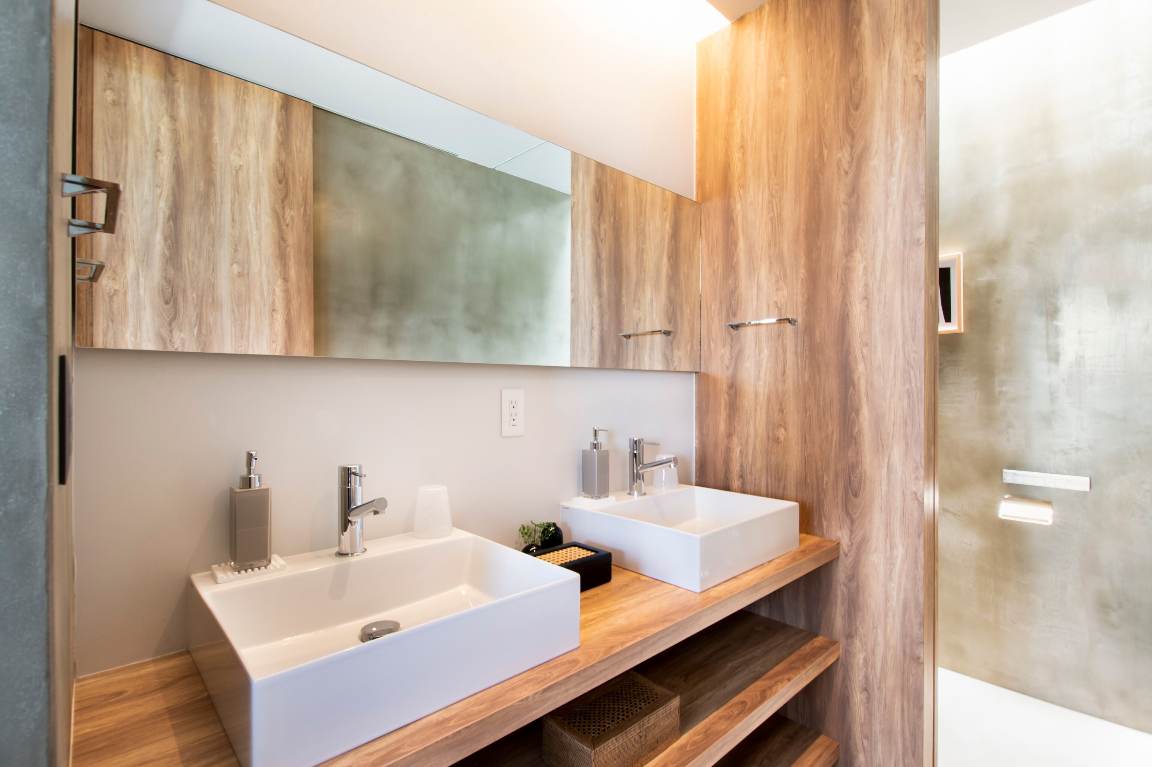A modern bathroom with two white sinks, wooden vanity, and a large mirror.