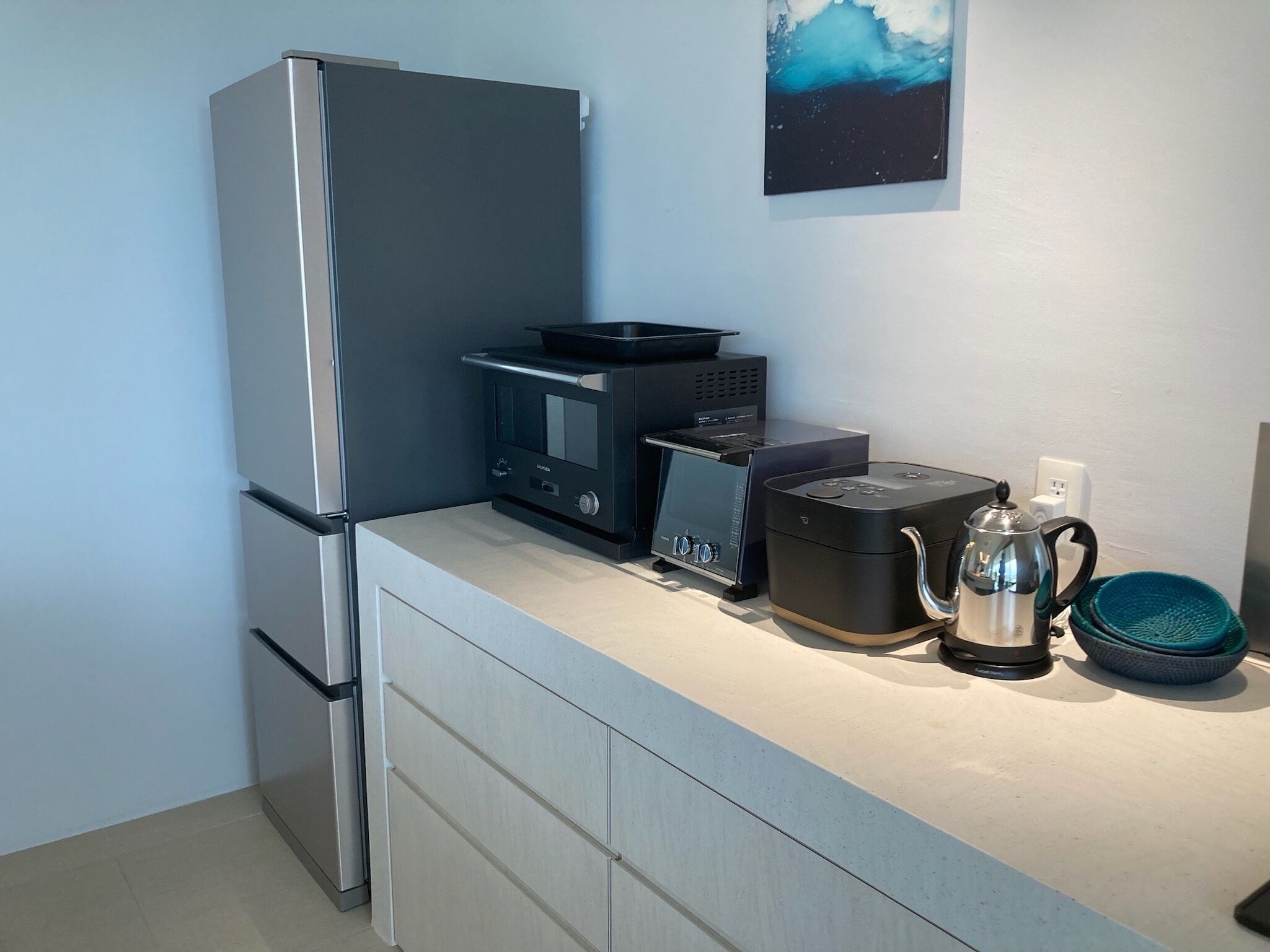 Una cocina compacta con refrigerador, microondas, tostadora y cafetera sobre la encimera.