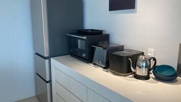 Una cocina compacta con refrigerador, microondas, tostadora y cafetera sobre la encimera.