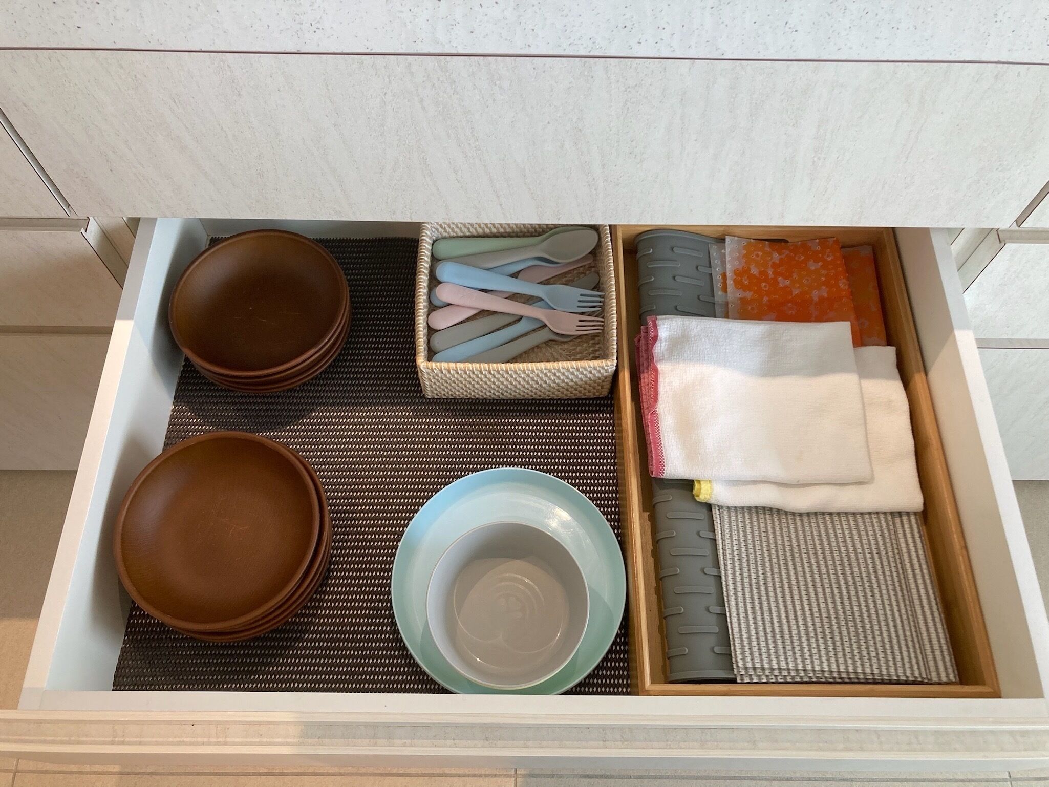 A kitchen drawer with various utensils and dishes.