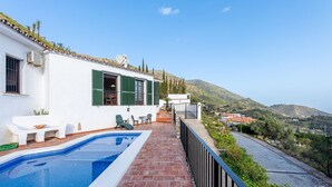 A poolside area with a white building, green shutters, and a view of a hilly landscape. - Spectacular Views Private Villa Valtocado (Mijas Pueblo)