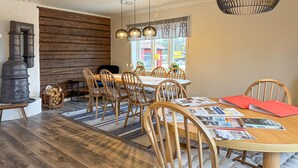 Zona pranzo con tavolo in legno, sedie, un grande piano cottura e lampade a sospensione.