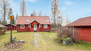 Una casa di legno rossa con tetto in tegole, un portico e un vialetto che conduce all'ingresso.