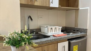 A kitchen with wooden cabinets, a microwave, a stove, and a refrigerator. - Laureles Grand House LGH Hotel - Anteriormente Laureles Guest House (Medellín)