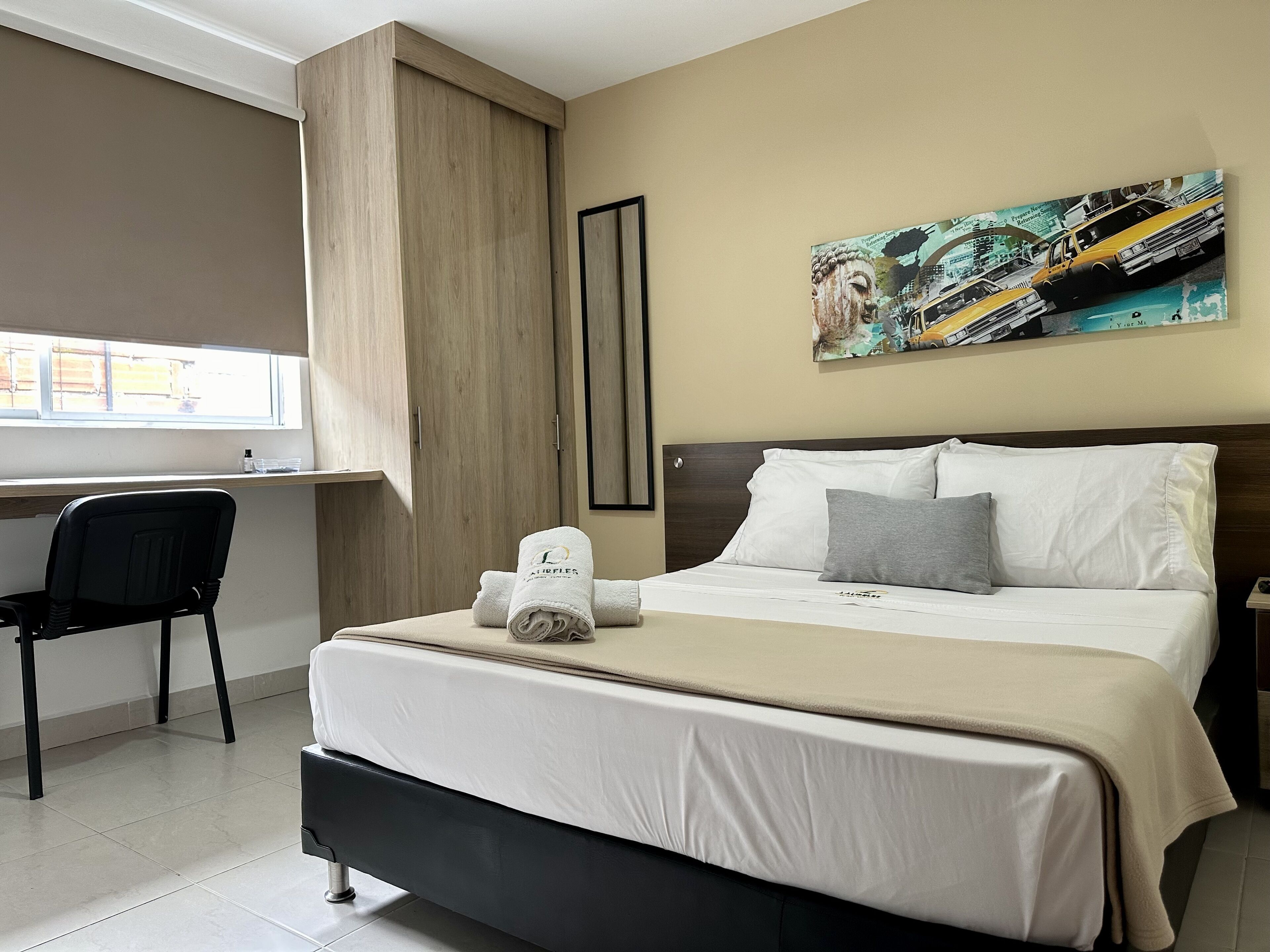 Quarto de hotel com cama, escrivaninha e cadeira.