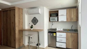 A modern kitchen with wooden cabinets, a stainless steel refrigerator, a microwave, and a sink. - Laureles Grand House LGH Hotel - Anteriormente Laureles Guest House (Medellín)