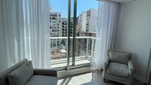 A modern living room with a large sliding glass door leading to a balcony, a sofa, and a chair. - Studio β Super (Buenos Aires)