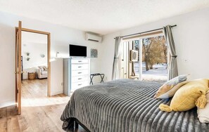 Une chambre à coucher avec un lit, une télévision, une commode et une fenêtre avec des rideaux.