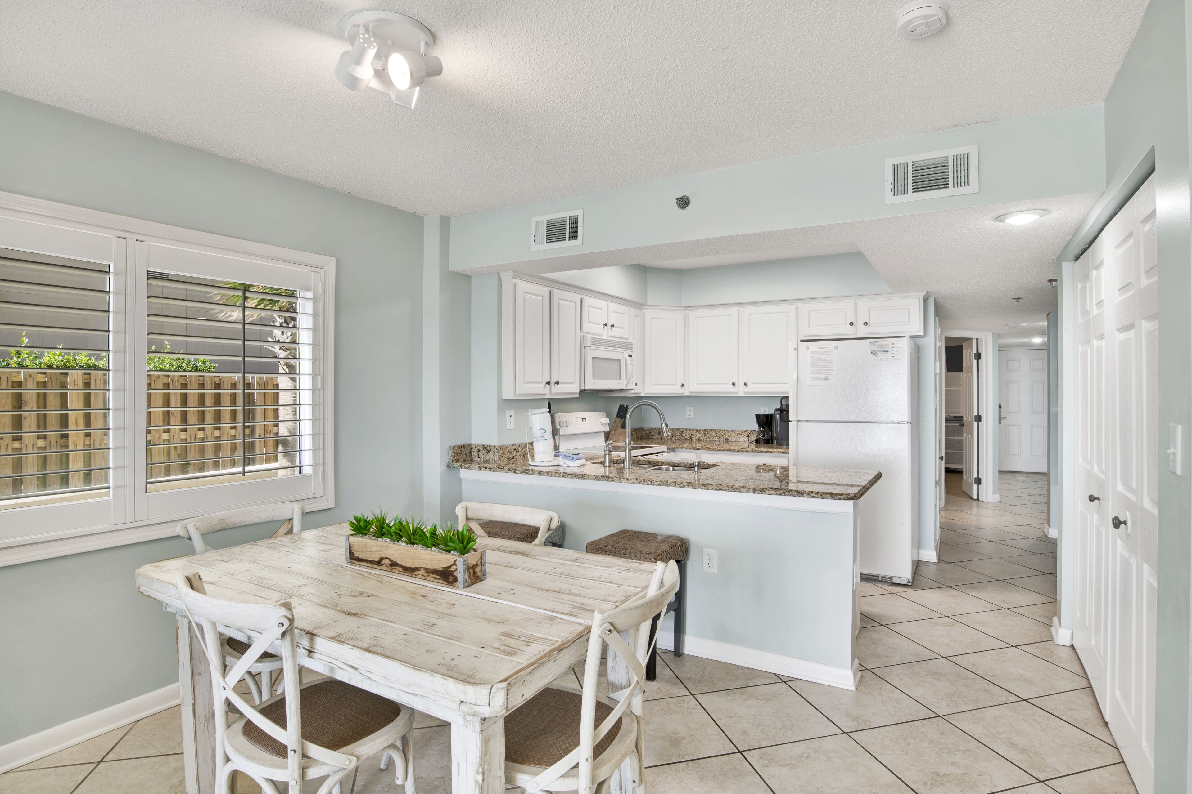 A kitchen with white cabinets, a central island, and a dining area with a table and chairs.