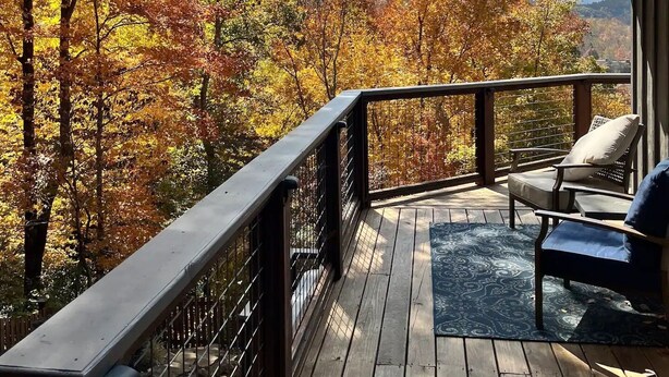 A wooden deck with a railing, a chair, and a view of autumn foliage. - Location Location  Location ! Resort Pools , Hot Tub ! MILLION DOLLAR VIEW !! (Gatlinburg)