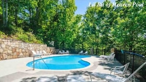 A swimming pool with lounge chairs and a stone wall. - Location Location  Location ! Resort Pools , Hot Tub ! MILLION DOLLAR VIEW !! (Gatlinburg)