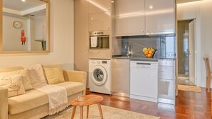 Un espacio habitable compacto con sofá, lavadora y zona de cocina.