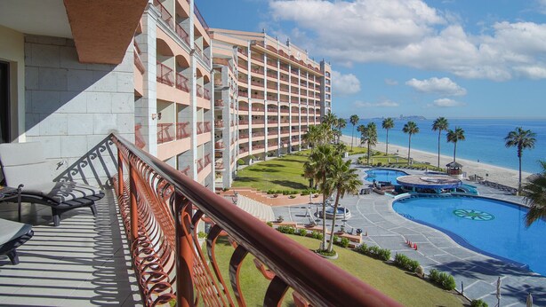 Un hotel con varios balcones que dan a una piscina y a la playa.