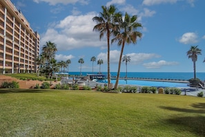 A resort with a pool, palm trees, and a view of the ocean.