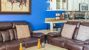 Un salón con sofás de cuero marrón, una mesa de centro y dos botellas de zumo de naranja.
