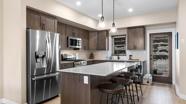 A modern kitchen with stainless steel appliances, wooden cabinets, and a central island with bar stools.