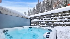 A hot tub with a stone wall and snow-covered ground.