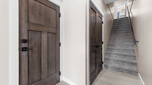 A hallway with two wooden doors and a carpeted staircase.